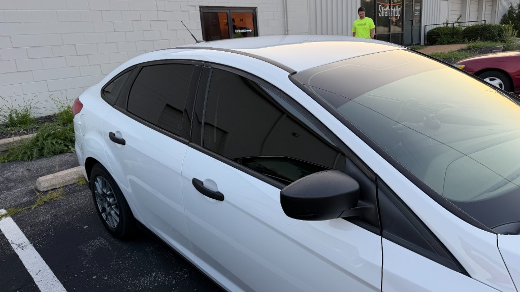 White sedan parked showing window tint shading under daylight
